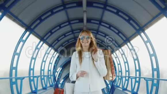 一个购物快乐的女人的肖像他正沿着玻璃隧道走微笑着良好的购物和旅游观念视频的预览图