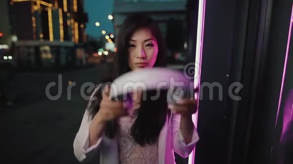 亚洲女人在城市夜间戴上耳机视频的预览图
