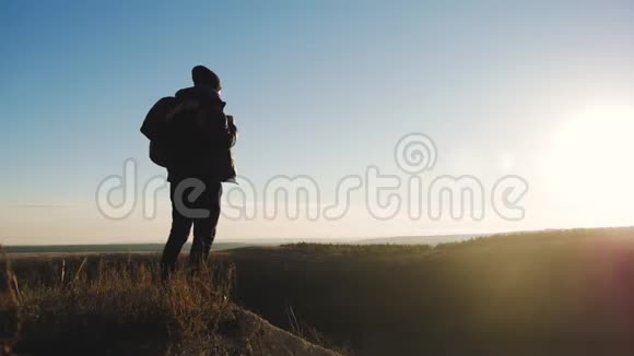 山中人的剪影背着背包站在山顶上的年轻人体育运动视频的预览图