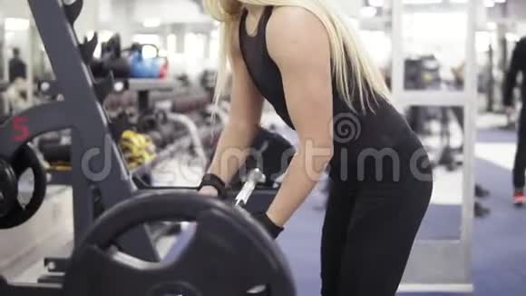 强壮的年轻金发女人有着漂亮的运动身体用健身带把手臂绑在杠铃上视频的预览图