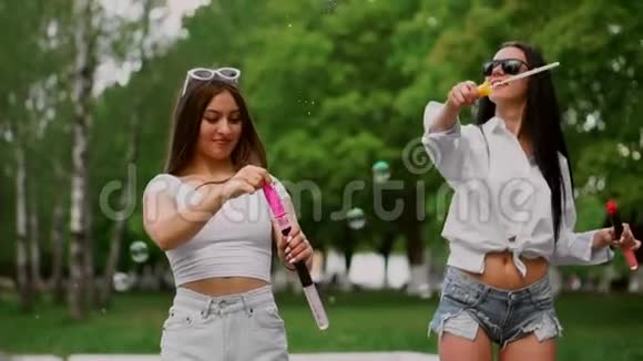 公园里的两个年轻漂亮的女孩正在笑正骑着公园里的一辆赛格威慢悠悠地吹着泡泡视频的预览图