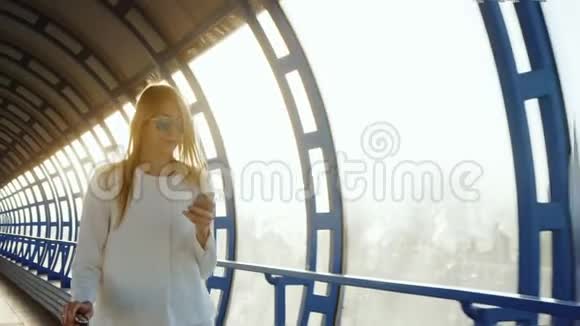 一个成功而有目的的女人穿过玻璃隧道使用智能手机夕阳照耀着她视频的预览图