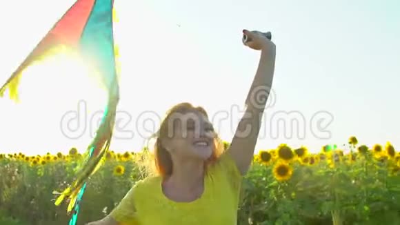 红长发的美女带着风筝在黄色的向日葵田上奔跑户外快乐的女人少年青少年视频的预览图