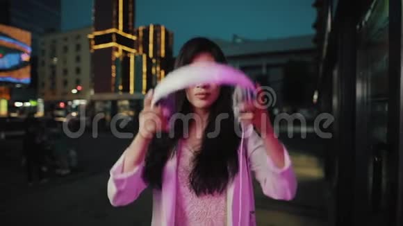 亚洲女人在城市夜间戴上耳机视频的预览图