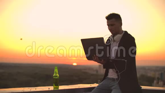 带笔记本电脑的人在屋顶边缘工作中的自由职业者无线移动互联网他在工作视频的预览图