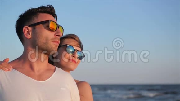 在阳光明媚的风日蓝天背景下可爱的男人和女人在时尚太阳镜的侧面视图视频的预览图