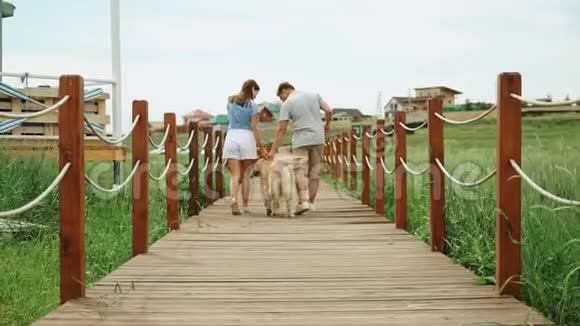 年轻夫妇带着猎犬木桥乡村慢动作离开视频的预览图