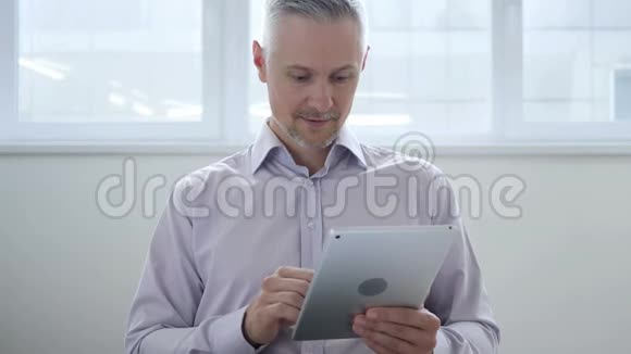 使用平板电脑时中年男子兴奋不已视频的预览图