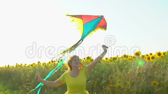 红长发的美女带着风筝在黄色的向日葵田上奔跑户外快乐的女人少年青少年视频的预览图