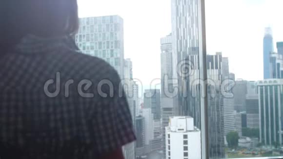 年轻女子走路的剪影从办公室的窗户欣赏城市景色3840x2160视频的预览图