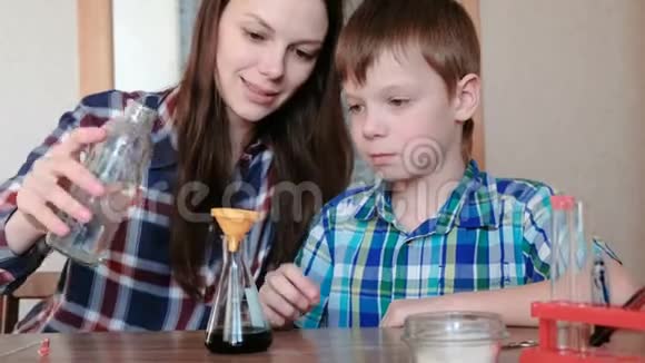 在家做化学实验女人用漏斗把水从瓶子里倒进瓶子里视频的预览图