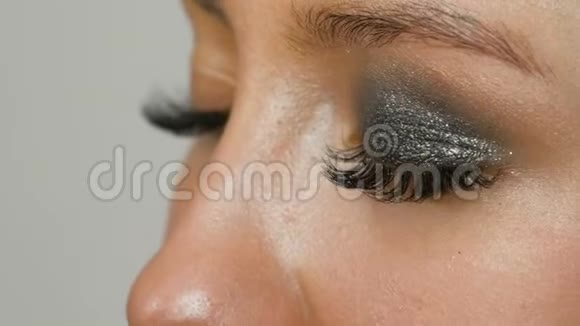 化妆师用特殊的画笔灰色眼影女孩的眼睛和睫毛制作出烟熏眼视频的预览图