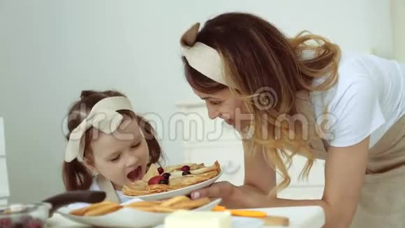 一个小女孩和她妈妈一起做煎饼和装饰浆果视频的预览图