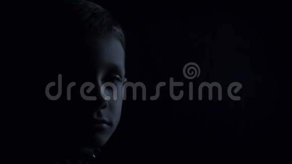 悲伤男孩特写半张脸在黑暗中视频的预览图