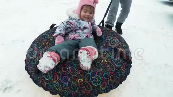冬天休闲娱乐的概念快乐的微笑女孩躺在雪橇上视频的预览图