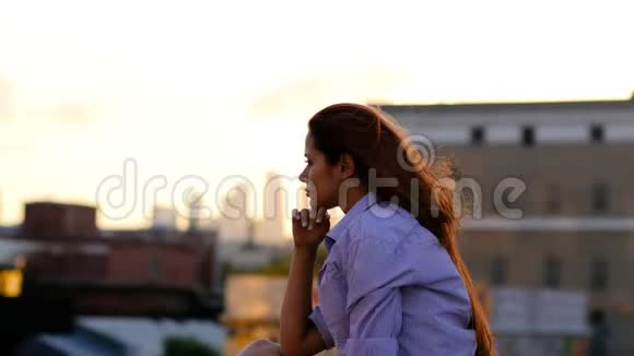 美丽的女人长发坐在屋顶上孤独的概念视频的预览图