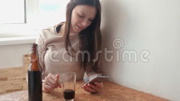 年轻漂亮的女孩在手机上通过社交网络上的磁带喝啤酒视频的预览图