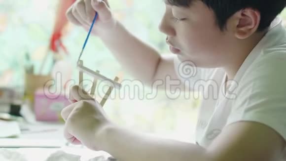年轻的亚洲男孩在家中用笑脸画水色视频的预览图