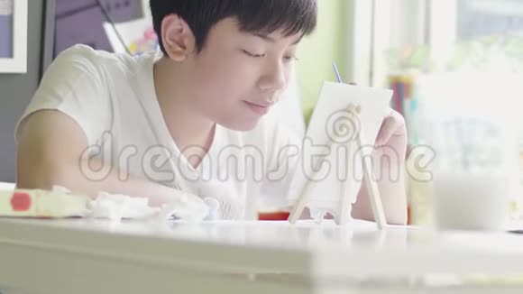 年轻的亚洲男孩在家中用笑脸画水色视频的预览图