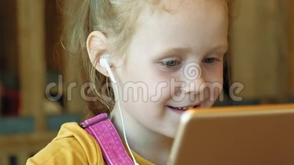 学龄前女孩在室内使用耳机电脑视频的预览图