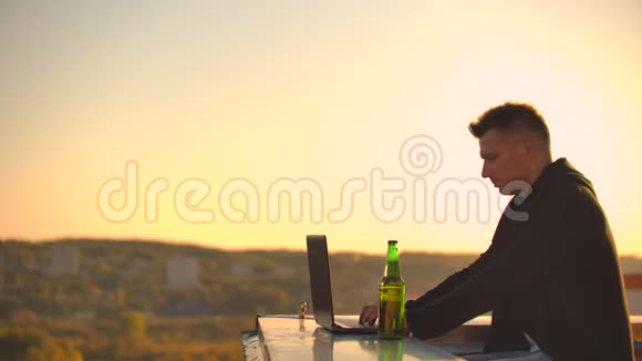 带笔记本电脑的人在屋顶边缘工作中的自由职业者无线移动互联网他在工作视频的预览图