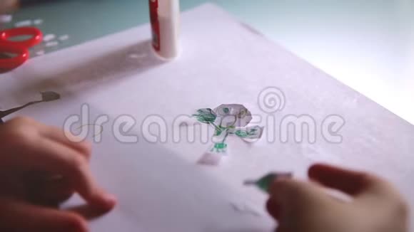 小女孩的手粉红色毛衣的特写镜头创造了有趣的人物形状从纸和胶水在桌子上视频的预览图