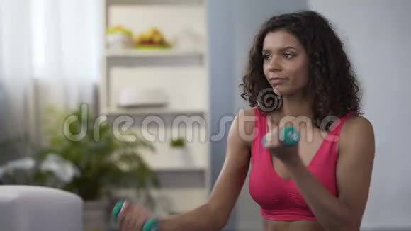 年轻女子交替举起哑铃锻炼身体护理控制体重视频的预览图