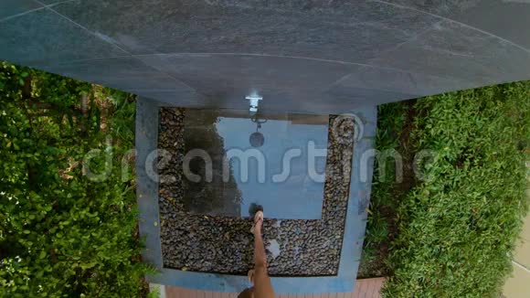 一个年轻女人在热带花园里洗澡的慢镜头在热带度假胜地度假的概念年轻女子视频的预览图
