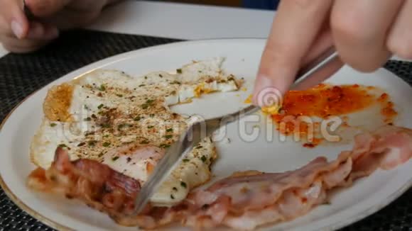 男性贵族用刀叉在白盘上用培根和红酱炒鸡蛋视频的预览图