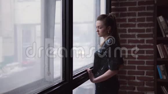 一位神情悲伤的年轻女子站在窗边视频的预览图