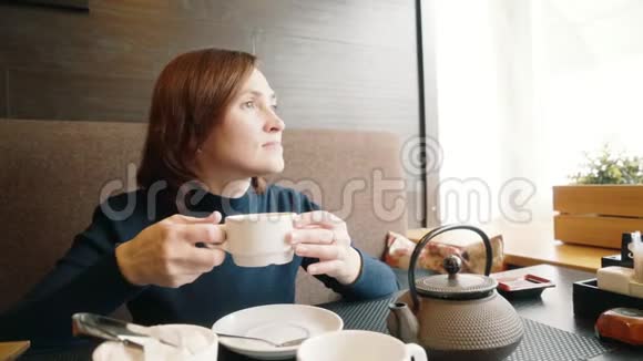 喝茶的女人一个漂亮的成年女孩拿着一个杯子手里拿着一杯热饮料背景是视频的预览图