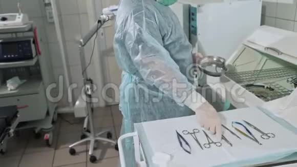 穿着长袍和口罩的外科医生从消毒器械中取出医疗器械并将一个夹子扔进去视频的预览图