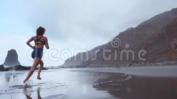 积极运动的女人沿着海边的水池冲浪以保持健康和健康日落黑沙滩背景视频的预览图
