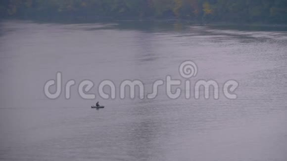 在阴寒的秋日船上的人漂浮在河上渔夫在池塘里钓鱼视频的预览图