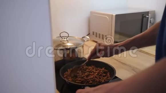 年轻人在厨房里做意大利面条腊肠薯条用平底锅中的酱汁切碎视频的预览图