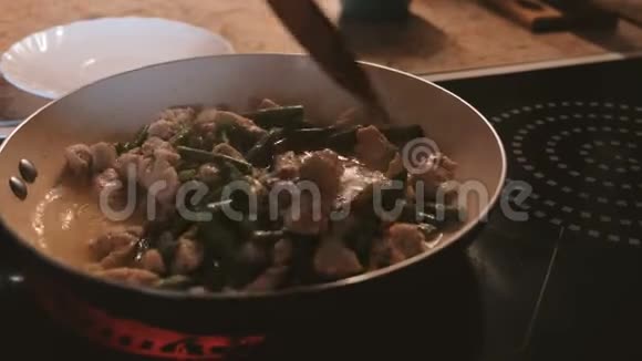 女人用平底锅里的豆子煎鸡用木抹子搅拌双手特写视频的预览图