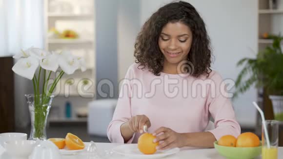 不分种族的年轻女性剪橘子对着镜头微笑健康的生活方式视频的预览图