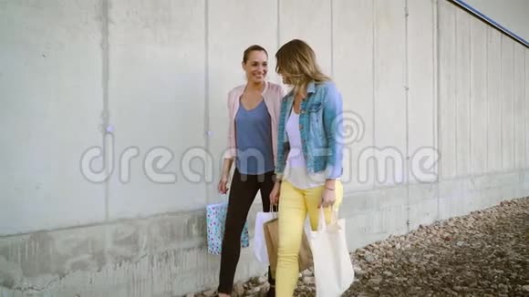 两个年轻漂亮的女人拿着购物袋走路视频的预览图