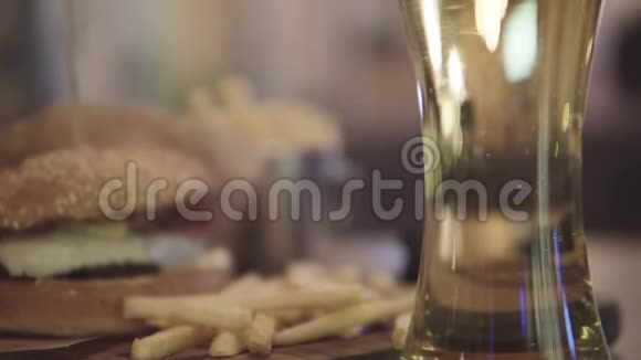 桌上有啤酒和薯条的汉堡包视频的预览图