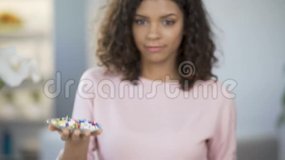 年轻女子手里拿着一盘药丸和橘子体重仿佛在秤上视频的预览图