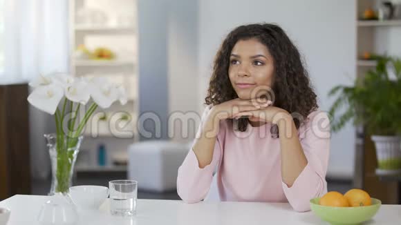 美丽的混血女人坐在桌子前做白日梦未来的计划视频的预览图