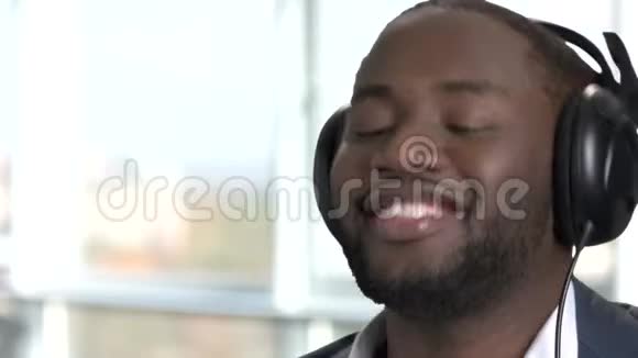 用耳机闭上快乐的非洲男人的脸视频的预览图