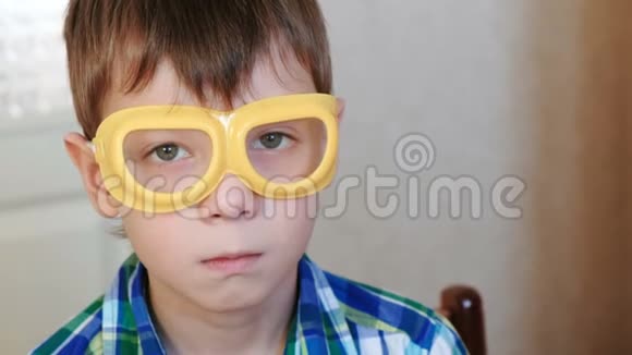 穿着安全黄色护目镜的色狼男孩坐在桌子旁看着相机家庭化学实验视频的预览图