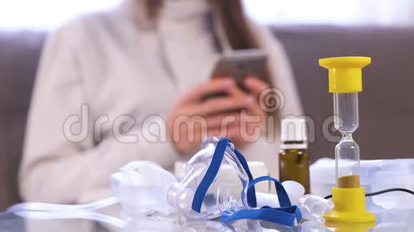 准备吸入雾化器口罩和药品放在玻璃桌上无法辨认的女人带着手机视频的预览图