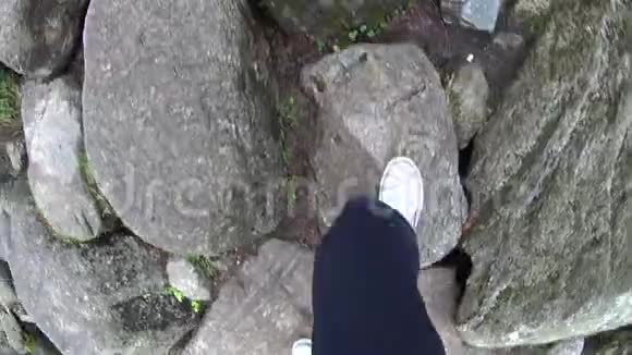 在徒步旅行的时候爬上一条岩石小路看着鞋子视频的预览图