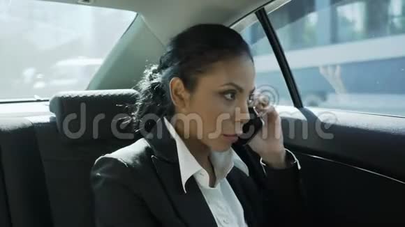 女商人坐在车后座打电话和朋友闲聊视频的预览图