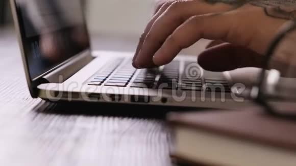 一个年轻人用手在笔记本电脑键盘上打字完成工作合上上网本视频的预览图