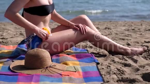沙滩上涂防晒霜的年轻女子视频的预览图