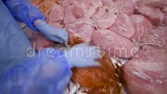 肉厂的员工用辣椒腌料铺鸡片为吸烟过程做准备视频的预览图