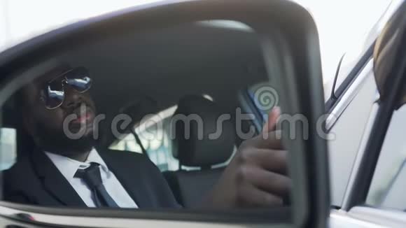 戴墨镜开车的非裔美国人看侧视镜保镖视频的预览图